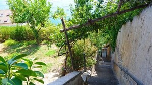 A narrow stone pathway flanked by greenery and a wall, leading to a building. - AMALFI "Casa Dipinta" SEA VIEW APT (AMALFI)