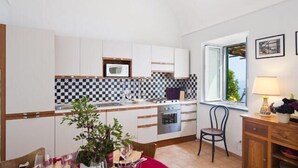 A compact kitchen with white cabinets, a microwave, and a checkered backsplash. - AMALFI "Casa Dipinta" SEA VIEW APT (AMALFI)