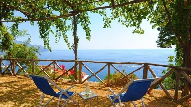 A beachside seating area with two blue chairs and a small table, overlooking the sea. - AMALFI "Casa Dipinta" SEA VIEW APT (AMALFI)