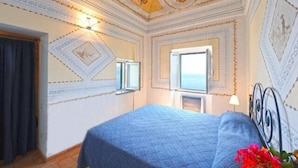 A hotel room with a large bed, a window with a view, and decorative ceiling patterns. - AMALFI "Casa Dipinta" SEA VIEW APT (AMALFI)