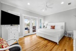 Un dormitorio con una cama, televisión, cómoda y ventilador de techo.