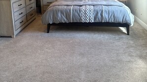 Ein Schlafzimmer mit einem Bett, Nachttischen, einer Kommode und zwei Wandleuchten.