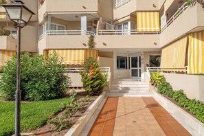 Stunning multi-story building with a central entrance, balconies, and a beautifully maintained garden.