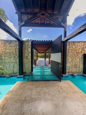 A covered pool area with stone walls and a wooden ceiling.