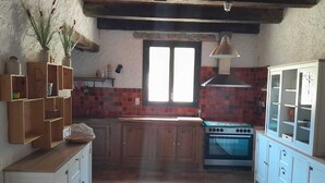 A kitchen with wooden cabinets, a stove, and a window. - Country house for rent in 7700 St-Marcel d'Ardèche (Saint-Marcel-d'Ardèche)
