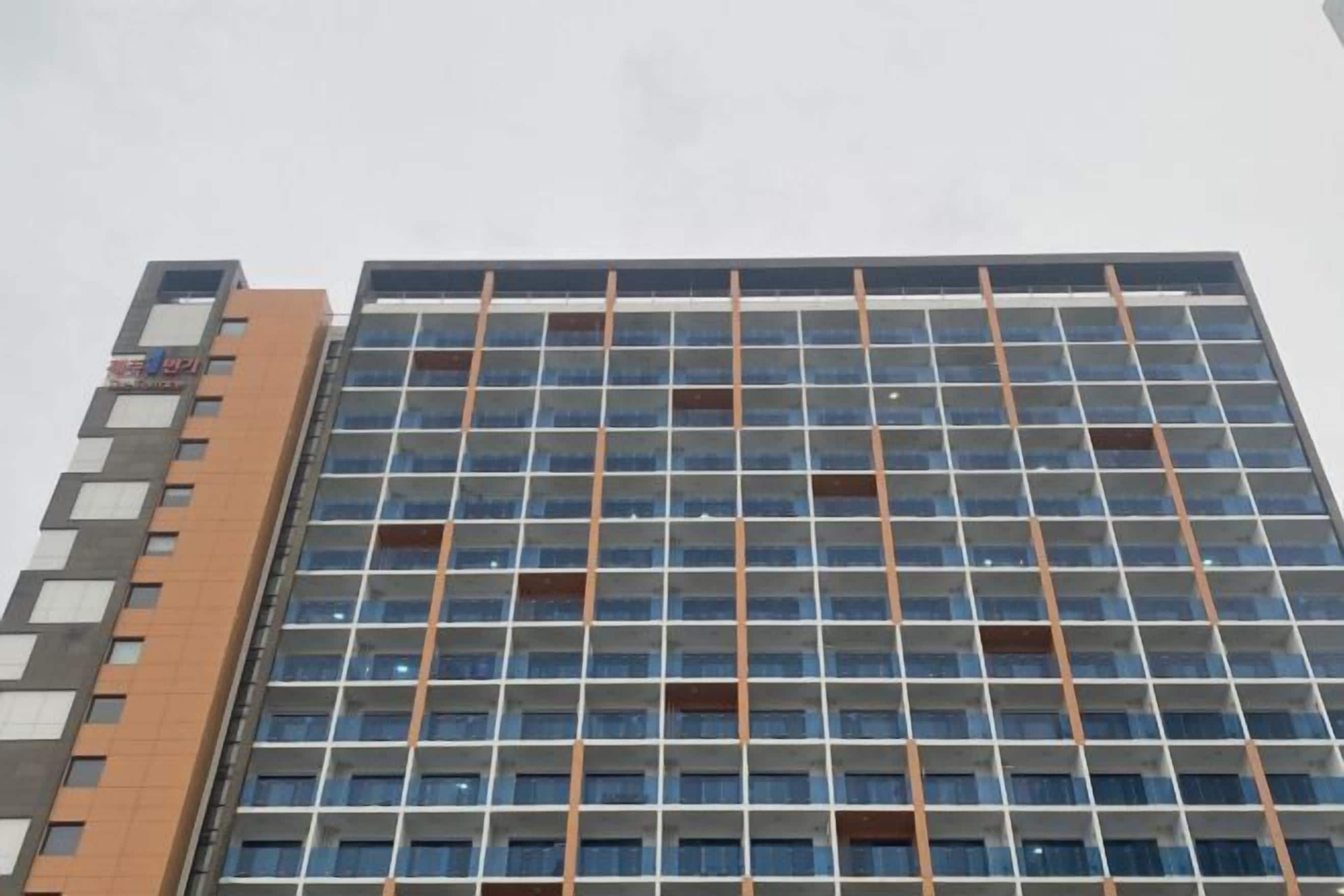 Un edificio de varios pisos con una fachada de color marrón y gris y una serie de ventanas.