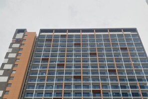 A multi-story building with a grid of windows and a mix of brown and grey exterior. - Jeju (Shinjeju) House (Jeju City)