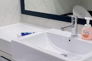 A bathroom sink with a mirror, a faucet, and a soap dispenser. - Jeju (Shinjeju) House (Jeju City)