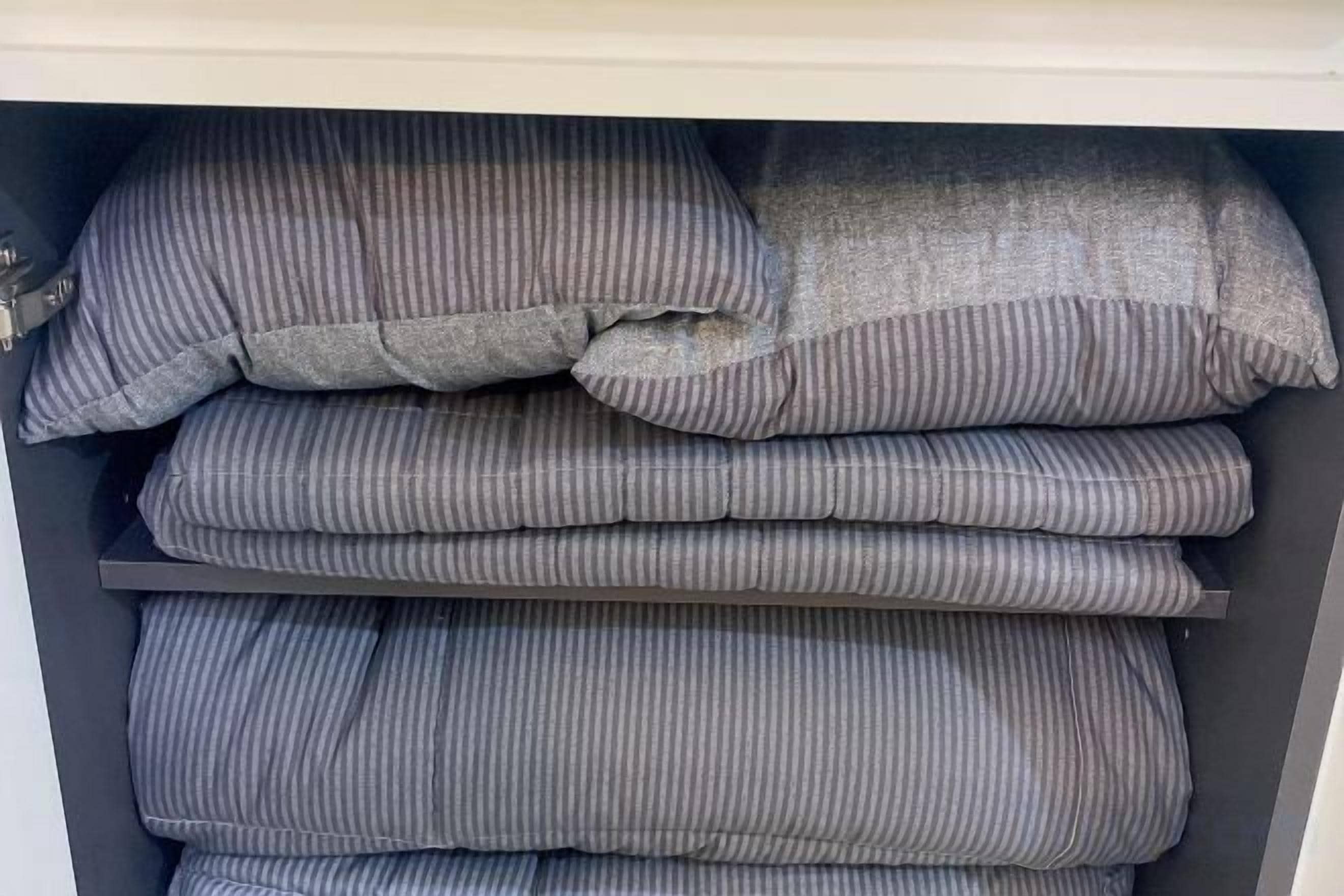 Un'area di stoccaggio con cuscini ordinatamente impilati e coperte piegate.