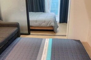 A bedroom with a bed, a sofa, and a sliding door leading to another room. - Jeju (Shinjeju) House (Jeju City)