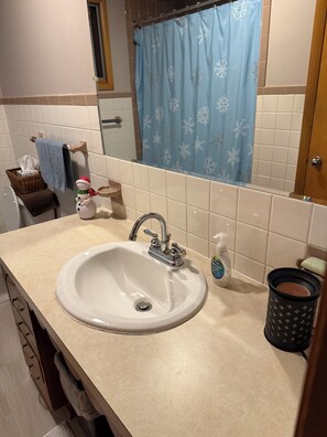 Une salle de bain avec un lavabo, un miroir et un rideau de douche bleu.