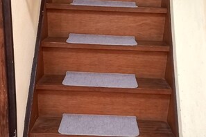 A wooden staircase with grey carpeted steps. - Lucky House Guest House (Osaka)