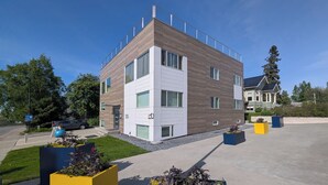 Un immeuble moderne à plusieurs étages, doté de grandes fenêtres, d’un toit plat et d’une entrée bien visible.