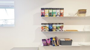 Une petite cuisine équipée d’un four à micro-ondes, d’étagères remplies de provisions et d’une fenêtre.