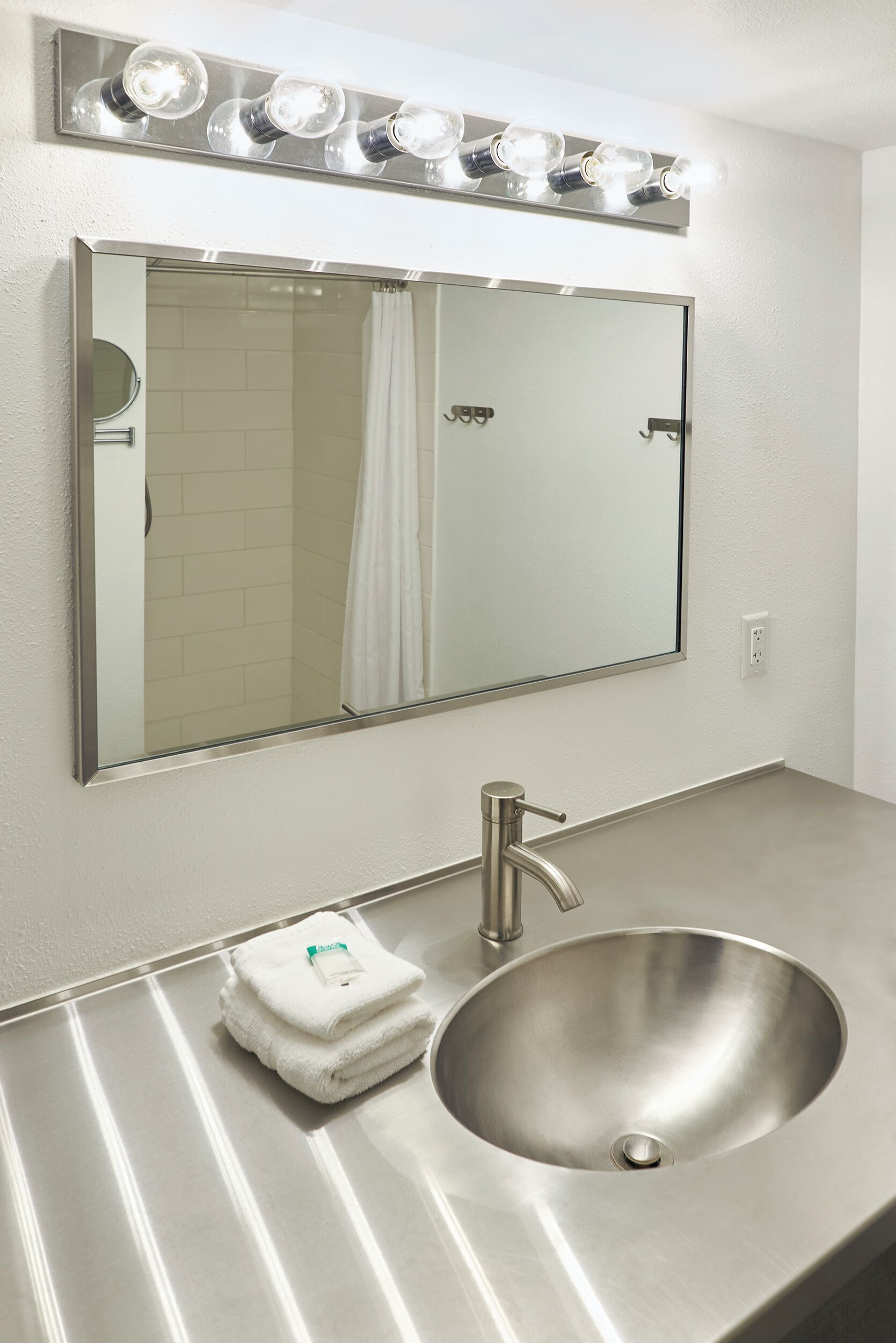 A bathroom with a large mirror, a sink, and a towel.
