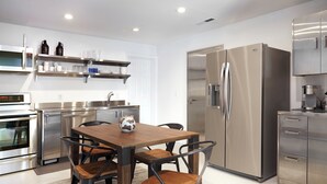 Une cuisine moderne équipée d’appareils électroménagers en acier inoxydable, avec une table à manger en bois et des chaises assorties.