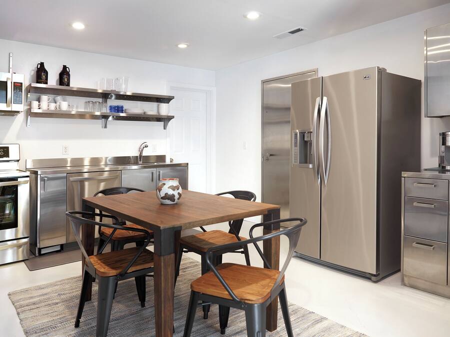 A modern kitchen with stainless steel appliances, a wooden dining table, and matching chairs.