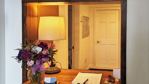 Un bureau en bois orné d’un vase de fleurs, d’une lampe, d’un bloc-notes et d’un stylo.