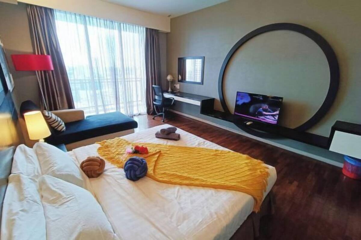 Una habitación de hotel con cama, escritorio, televisión y un ventanal con cortinas.