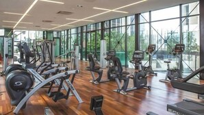 A gym with various exercise machines, large windows, and a wooden floor. - Shore Hotel Melaka Private Suites (Melaka)