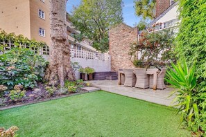 Relax in a serene outdoor space with a seating area, lush plants, and a walled garden.