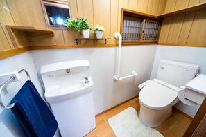 Une petite salle de bain comprenant des toilettes, un bidet et une petite étagère avec des plantes.