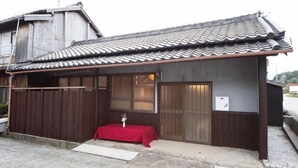 Un edificio tradicional japonés con tejado de tejas, paredes de madera y una pequeña mesa cubierta con un paño rojo.