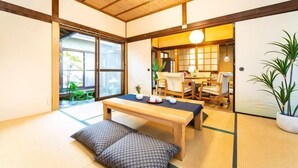 Ein traditioneller japanischer Raum mit Tatami-Bodenbelag, einem niedrigen Holztisch und einer verschiebbaren Tür zu einem weiteren Raum.