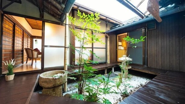 Ein traditionelles japanisches Interieur mit Tatami-Böden, einem Steinbecken und einem kleinen Baum.