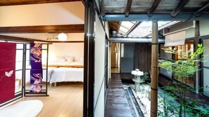 Ein traditioneller japanischer Raum mit Tatami-Boden, einer niedrigen Holzdecke und einer Schiebetür mit dekorativem Trennwerk.