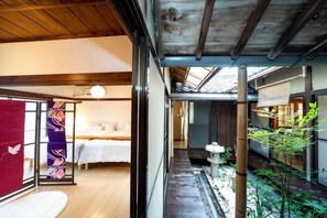 Habitació japonesa tradicional amb tatami, sostre de fusta baix i porta corredissa amb un panell decoratiu.