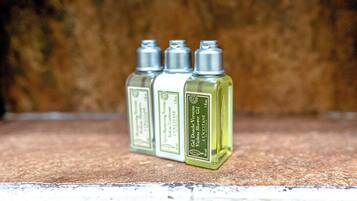 Three bottles of L'Occitane shower gel on a textured surface.