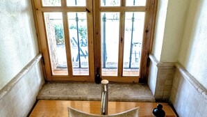 A bathroom with a unique, modern sink design, wooden flooring, and a view through a large window with metal railings.