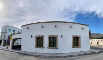 Un edificio blanco con tres ventanas y un techo curvo, situado en una esquina.