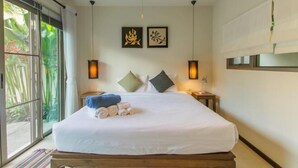 A hotel room with a bed, two wall-mounted lamps, and a window with curtains. - Emerald Pool Villa in Rawai (Phuket)