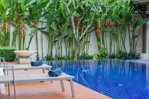 A pool area with lounge chairs, a stone bowl, and lush greenery. - Emerald Pool Villa in Rawai (Phuket)