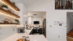 A modern kitchen with white cabinetry, a built-in microwave, and a stainless steel refrigerator.