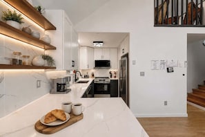 A modern kitchen with white cabinetry, a built-in microwave, and a stainless steel refrigerator.
