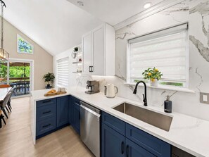 A modern kitchen with a dishwasher, a coffee machine, and a sink.