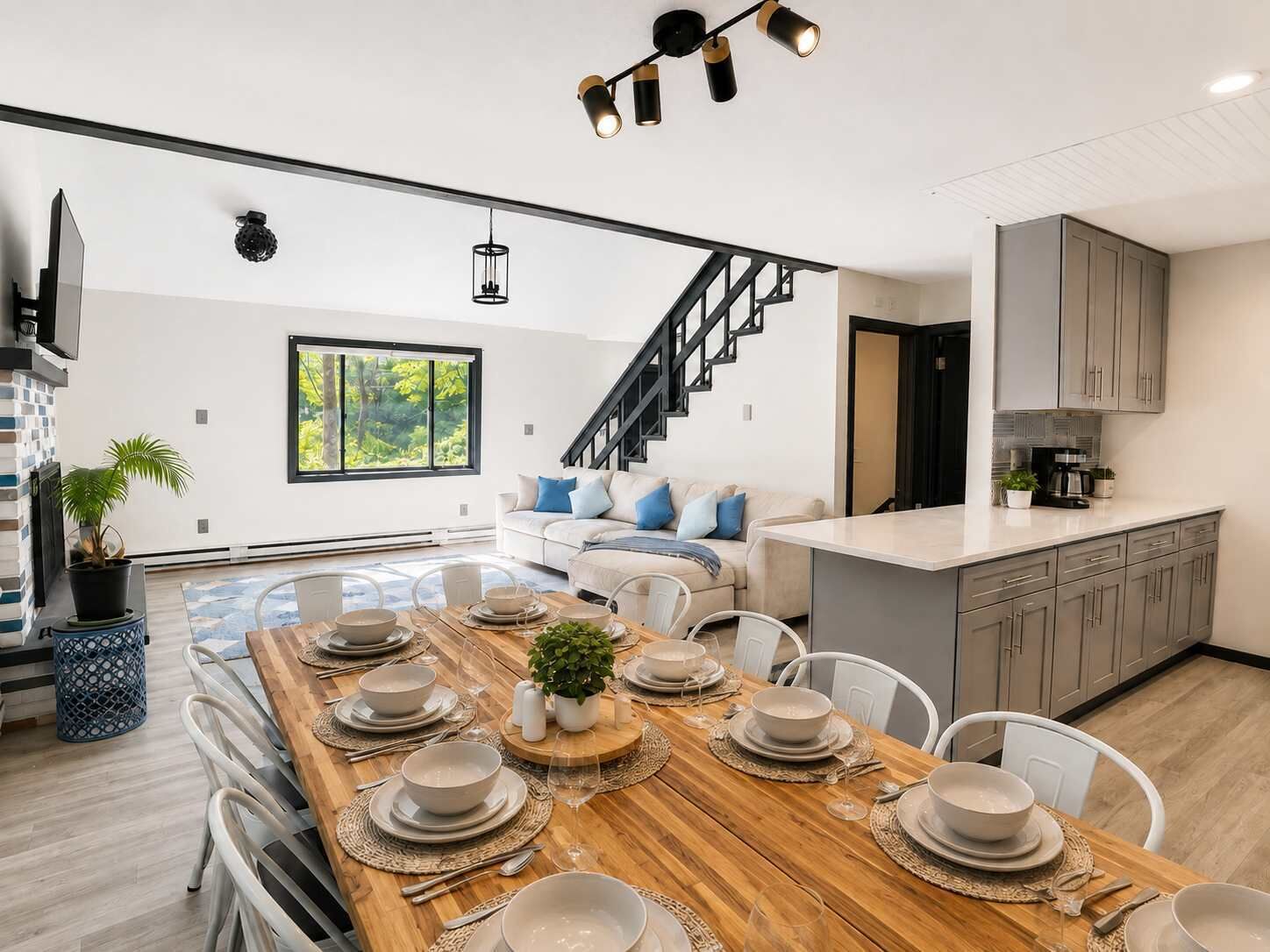 Une cuisine moderne avec un coin repas, un escalier et une vue sur la verdure.