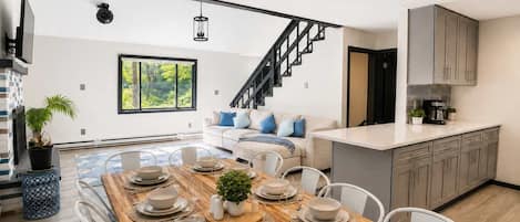 Une cuisine moderne avec un coin repas, un escalier et une vue sur la verdure.