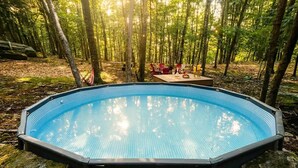 An outdoor swimming pool surrounded by a forest. - Cozy Forest Retreat with Hot Tub, Sauna, Pool (East Stroudsburg)