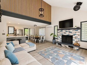 En moderne stue med sofa, spiseområde og pejs.