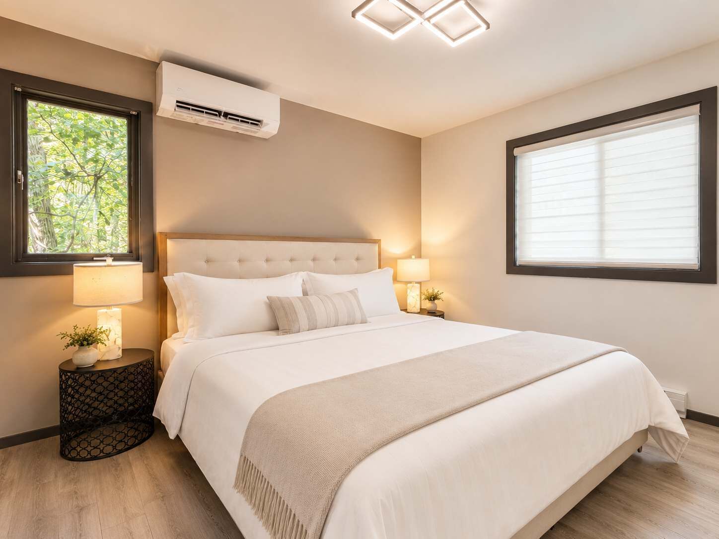 Een slaapkamer met een bed, twee nachtkastjes, een raam, een airconditioner en een plafondlamp.