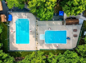 Vista aérea de una propiedad con dos piscinas, un área de estar techada y un edificio pequeño.