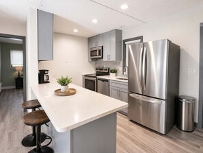 Een moderne keuken met een groot eiland, roestvrijstalen apparatuur en een minimalistisch ontwerp.