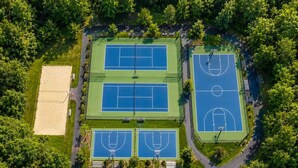 An aerial view of a sports complex with multiple tennis courts, a basketball court, and a sand court. - Cozy Forest Retreat with Hot Tub, Sauna, Pool (East Stroudsburg)