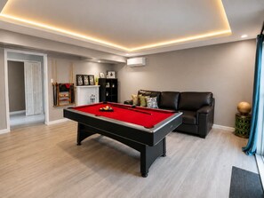 Un salon moderne avec une table de billard, un canapé en cuir et un porte-taquets.