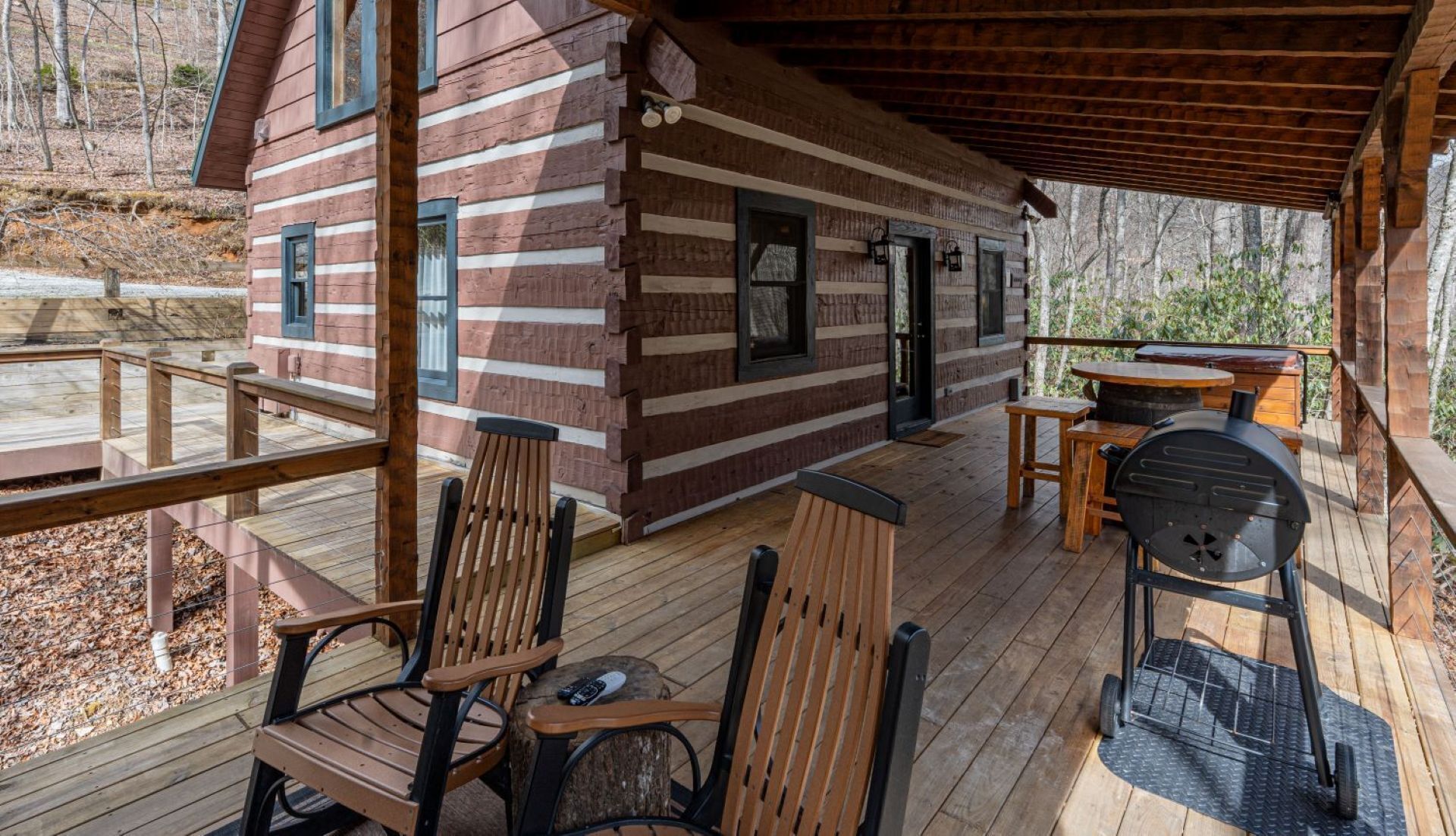 Une cabane en rondins dotée d’une terrasse, d’un espace salon extérieur et d’un barbecue.