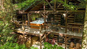 A cabin with a hot tub on the deck, surrounded by trees. - Cherokee Lodge-Pet Friendly, Luxury Log Cabin Rental, Hot Tub, 2 Fireplaces, Fishing- Nantahala NC. (Topton)